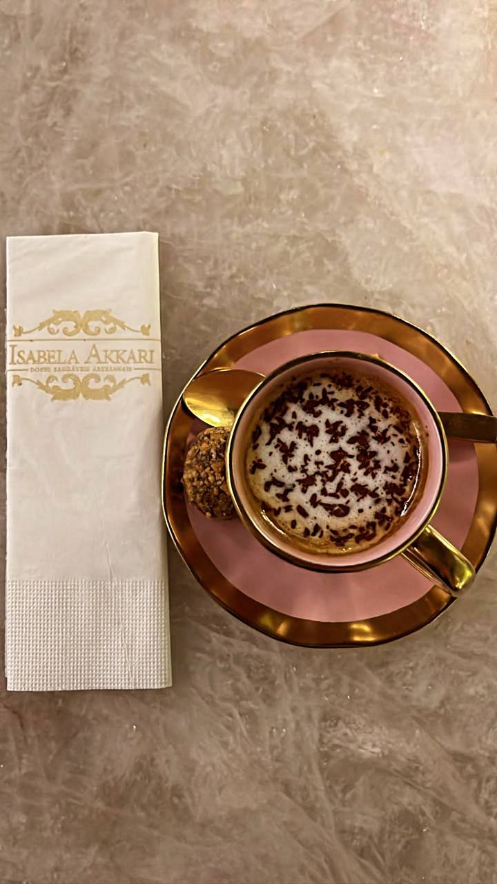 Café Isabela Akkari em xícara rosa com pires dourado e biscoito decorado